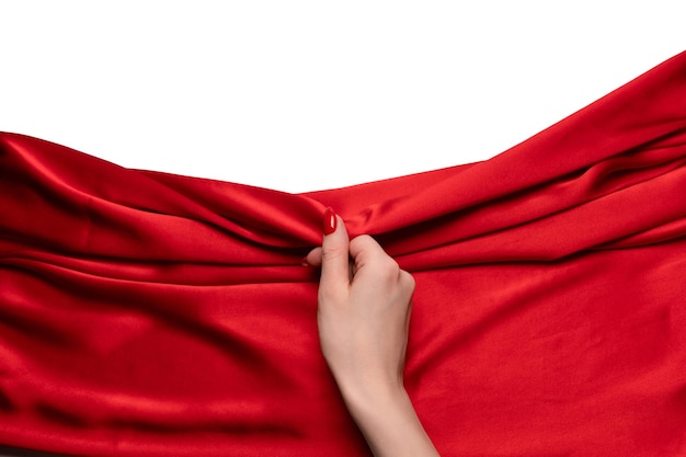 De hand van een vrouw met rode nagels probeert een rode zijden stof eraf te trekken