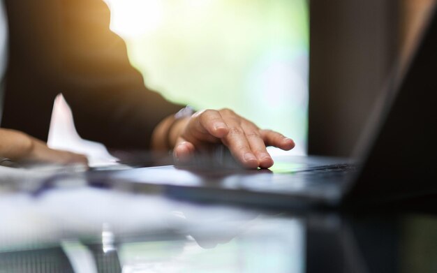 De hand van een zakenvrouw die het touchpad van een laptop aanraakt terwijl ze op kantoor werkt