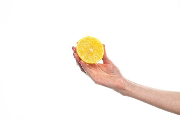 De hand van het meisje houdt een gesneden rond schijfje verse tropische sinaasappel vast Een sinaasappel in de hand van een vrouw op een witte achtergrond is geïsoleerd Schijfje sinaasappel Het meisje houdt zachtjes een citrusvrucht in de hand