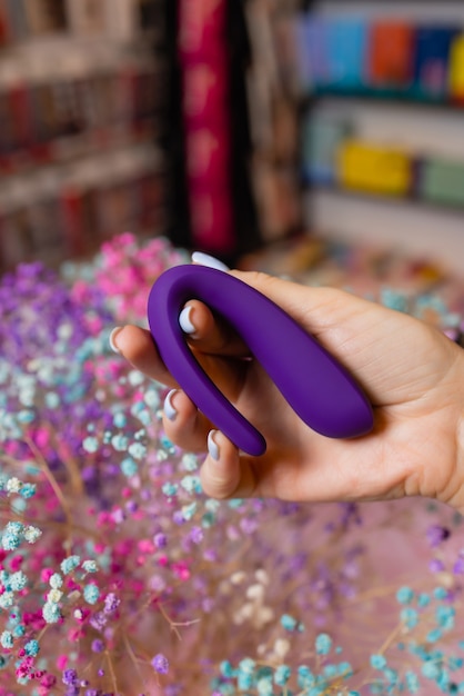 De hand van het meisje houdt een stimulator vast voor seks. Vibrator voor masturbatie. Dildo voor vaginale en clitorale stimulatie. Afbeelding voor seksshop.