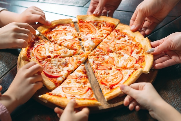 De handen die pizzaplakken van houten lijst nemen, sluiten omhoog mening.