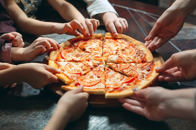 De handen die pizzaplakken van houten lijst nemen, sluiten omhoog mening.