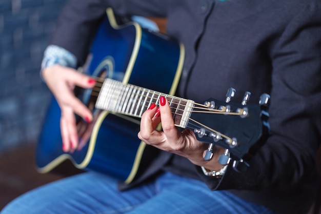 De handen die van de vrouw akoestische gitaar spelen, sluiten omhoog