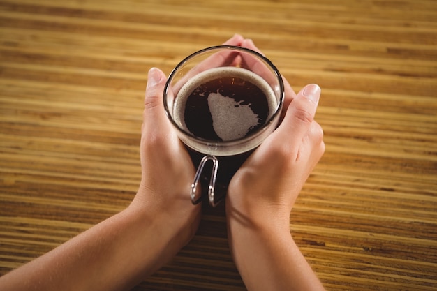 De handen die van de vrouw de kop van koffie houden