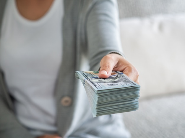 De handen die van de vrouw geld voorstellen ons dollarrekeningen aan u.