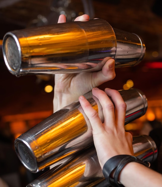 De handen van de barman houden een professionele shaker vast tegen de toog.