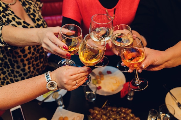 De handen van de bejaarde met een glas wijn die voor een ander glas wijn bereiken.