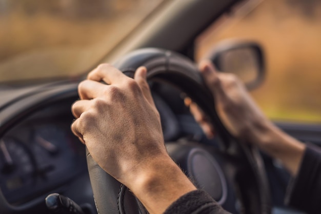 De handen van de bestuurder op het stuur in een auto