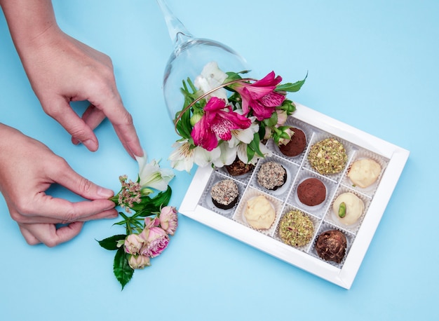 Foto de handen van de bloemist versieren met bloemen een doos chocolade handgemaakt uit witte cho