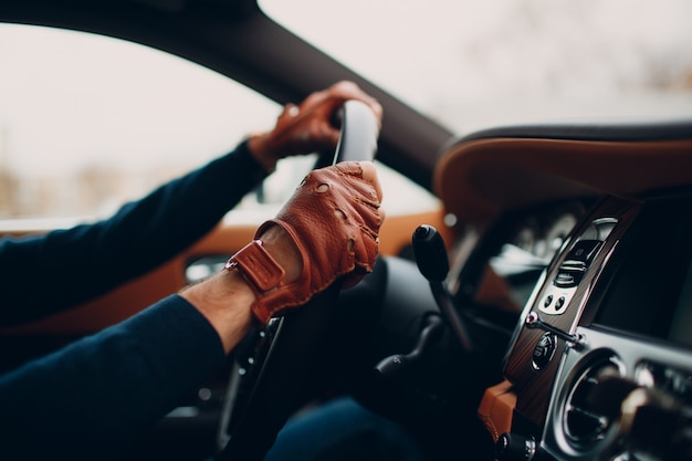 De handen van de chauffeur in leren handschoenen, het besturen van een rijdende auto.