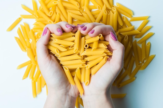 De handen van de chef-kok die Italiaanse pasta in zijn handen houdt