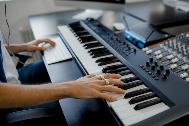 De handen van de componist op pianosleutels in opnamestudio