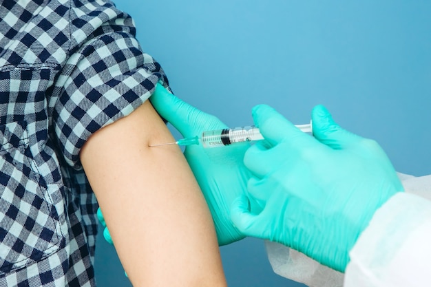 De handen van de dokter zijn van dichtbij. de arts geeft de persoon een injectie. Seizoensgebonden vaccinatie. Inenting.