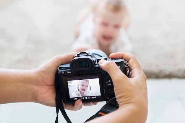 De handen van de fotograaf nemen een foto van een schattige baby.