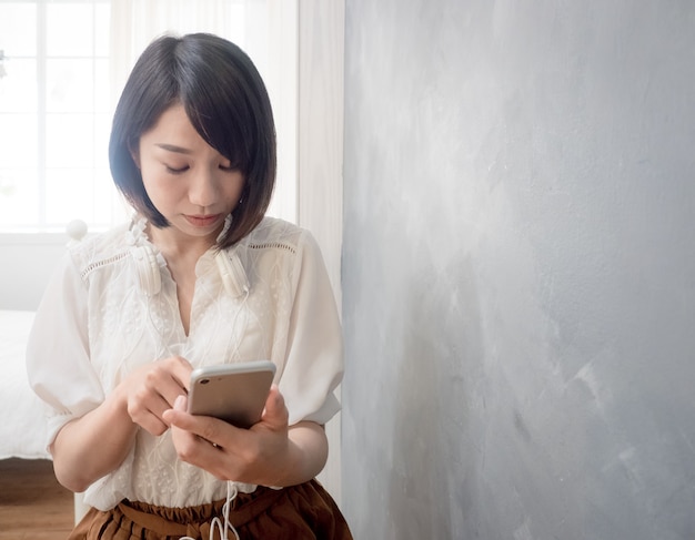 De handen van de jonge aziatische vrouw met mobiele telefoon