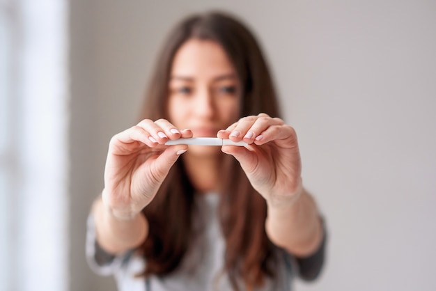 De handen van de jonge vrouw die een sigaret houden en haar breken