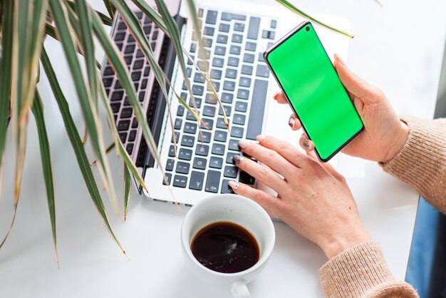 De handen van de jonge vrouw die haar telefoon controleren. Focus op de chromakey van de mobiele telefoon, groen scherm.