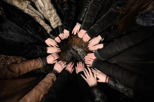 de handen van de kinderen zijn gevouwen met de handpalmen omhoog in een cirkel de handen worden over het vuur gehouden