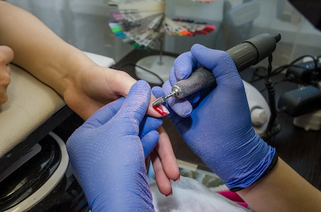 de handen van de meester verwijderen de vernis van de nagels van de klant in de manicuresalon