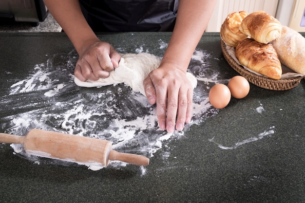 De handen van de vrouw kneden deeg met bloem, eieren en ingrediënten. in de keuken.