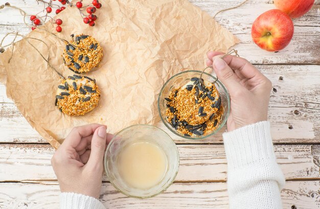 De handen van de vrouw maken voedsel voor wilde vogels van appelbacon en zaden