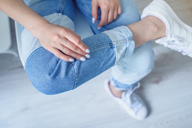 De handen van de vrouw met perfecte manicure dragen een spijkerbroek en een wit basic t-shirt