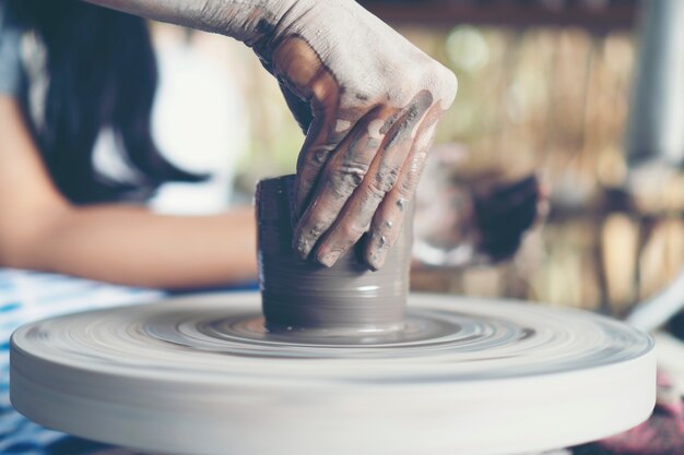 De handen van de vrouw sluiten zich op, het meesterlijke atelier van keramiek werkt met klei