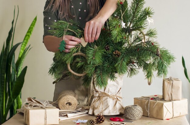 De handen van de vrouw versieren sommige naaldtakken met ornamenten van natuurlijke materialen