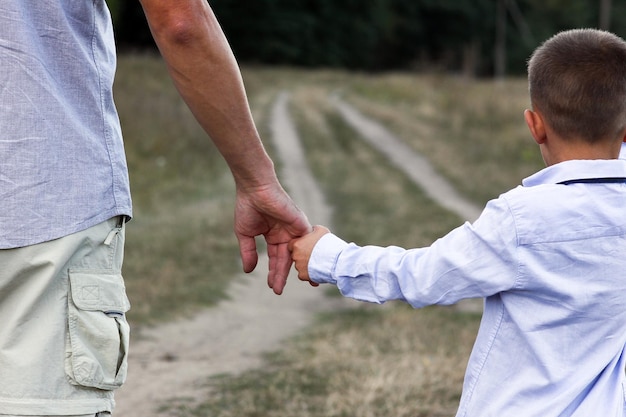 De handen van een gelukkig kind en van ouders op aard in de parkreis