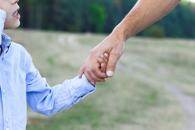 De handen van een gelukkig kind en van ouders op aard in de parkreis