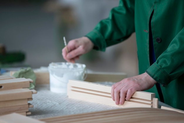 De handen van een houtbewerkingsfabriekarbeider lijmen houten stoelen van natuurlijk hout