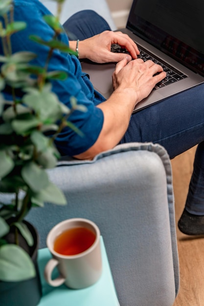 De handen van een jonge man op het toetsenbord van een laptop thuis of in een café werken op afstand of online winkelen