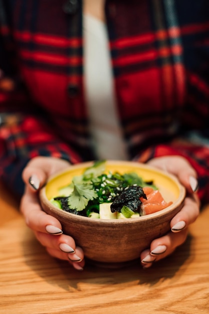 De handen van een jonge vrouw houden een bord verse salade vast