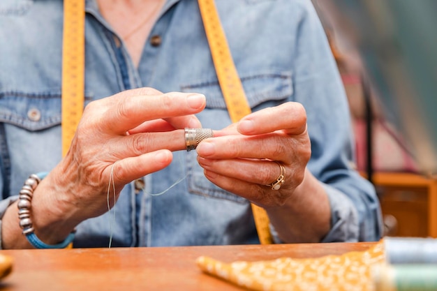 De handen van een oudere vrouw die een vingerhoed omdoen