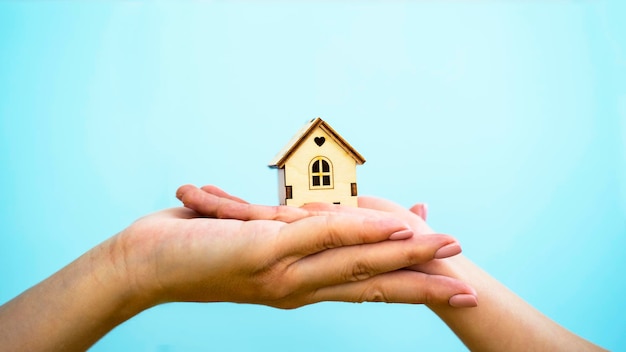 De handen van een volwassene en een kind houden een houten huis vast