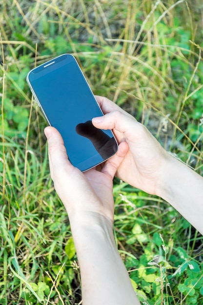 De handen van een vrouw die buitenshuis een smartphone gebruikt