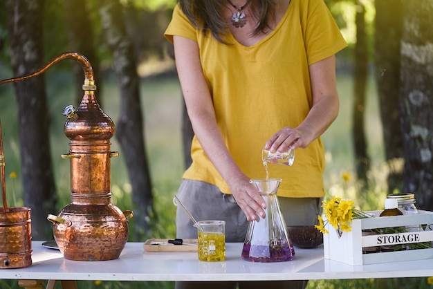 De handen van een vrouw maken essentiële oliën aan een werktafel in het veld