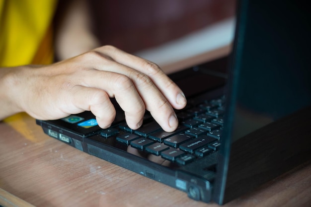 De handen van een zakenman die op een notebook-toetsenbord schrijft