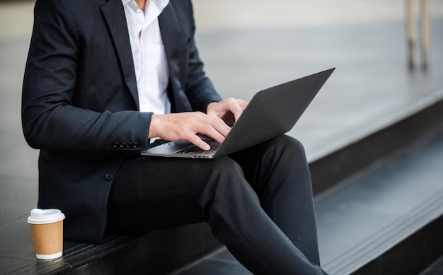 De handen van een zakenvrouw typen op het toetsenbord van een smartphone en laptop in een ochtendlichtcomputer die online typt buiten officexA