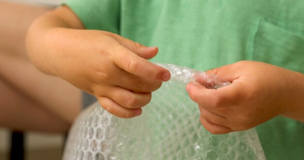 De handen van kinderen barsten polyethyleenbellen