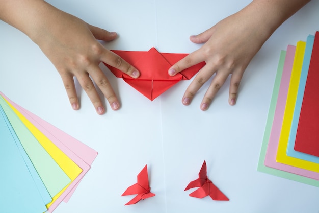 Foto de handen van kinderen doen origami een vlinder.