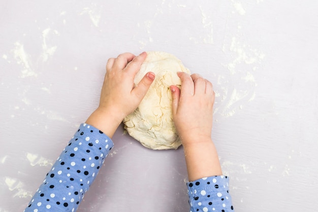 De handen van kinderen maken een deeg