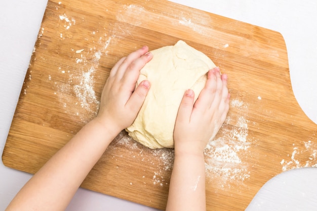 De handen van kinderen maken een deeg