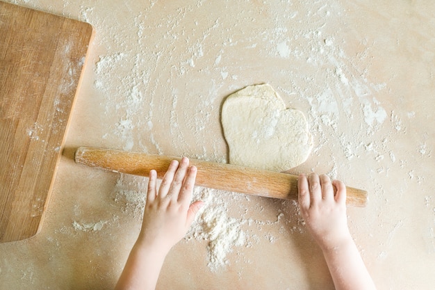 De handen van kinderen rolden deeg