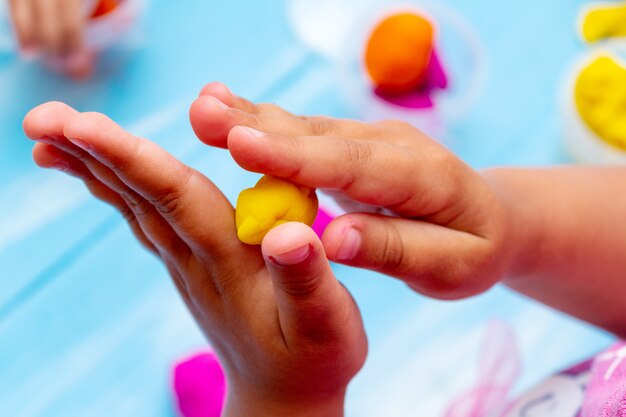 De handen van kinderen vormen kleurrijk deegclose-up. Jeugd kinderen baby's onderwijs concept