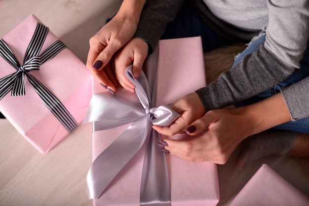 Foto de handen van moeder en dochter die een geschenk uitpakken