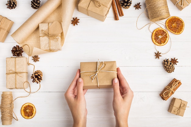 De handen van vrouwen bevatten een geschenk van ambachtelijk papier.