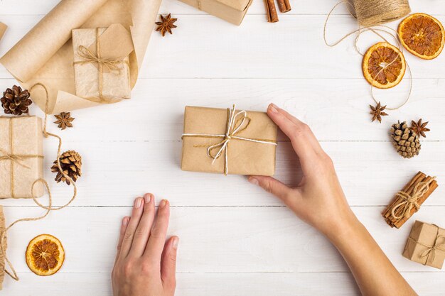 De handen van vrouwen bevatten een geschenk van ambachtelijk papier.