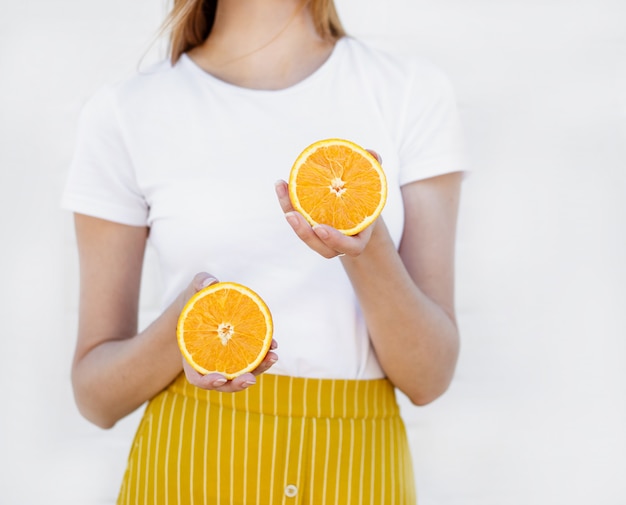 De handen van vrouwen houden een sappige halve sinaasappel die op wit wordt geïsoleerd