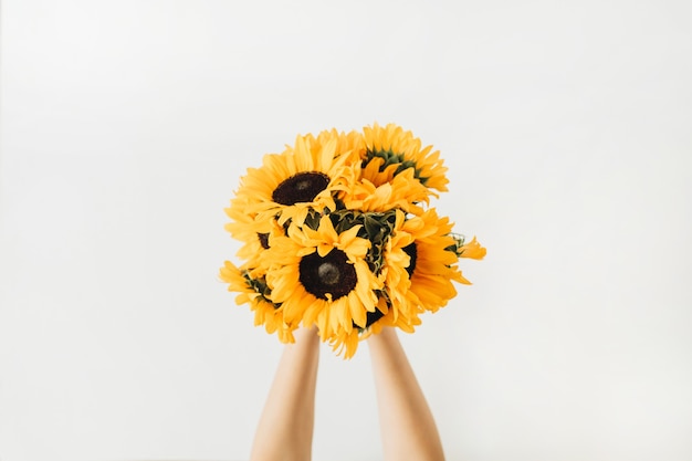 De handen van vrouwen houden geel zonnebloemenboeket op wit